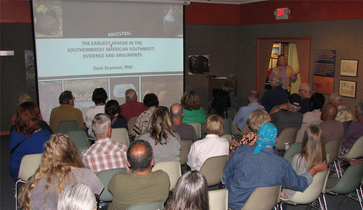Woman giving presentation to crowed of sitting people.